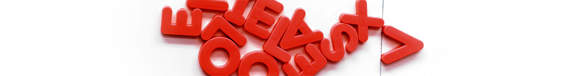 Buchstabensalat. Rote magnetische Buchstaben liegen durcheinander auf weißem Hintergrund.